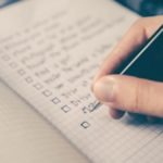 man writing down on paper using ivy lee method