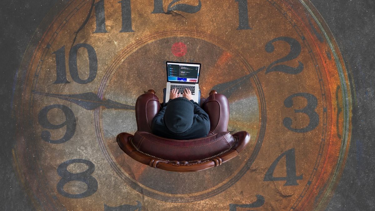 man wasting time on laptop sitting in middle of painted clock