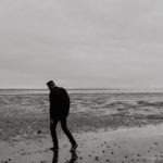 lonely man walking on beach